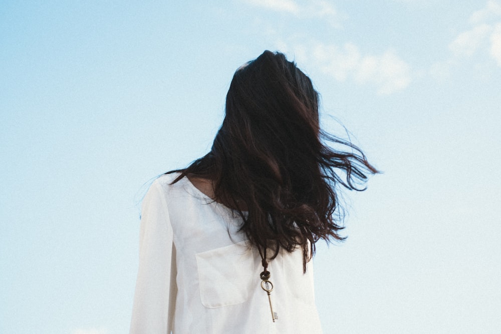 Mujer con camisa blanca bajo cielo nublado