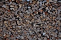 Stacked firewood pieces arranged neatly, showcasing various shades of brown and textures. The logs are cut into similar sizes and organized tightly together, highlighting their natural grain.