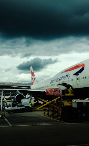 white and red airplane with cumulonimbus cloud