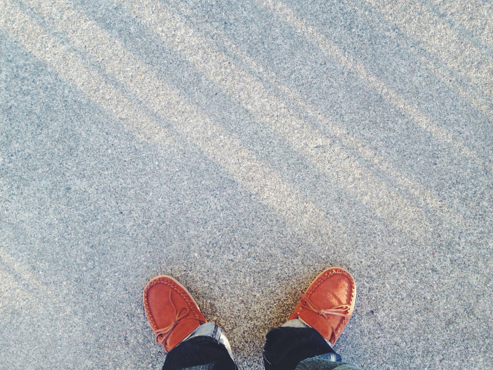 person wearing pair of brown boat shoes on floor