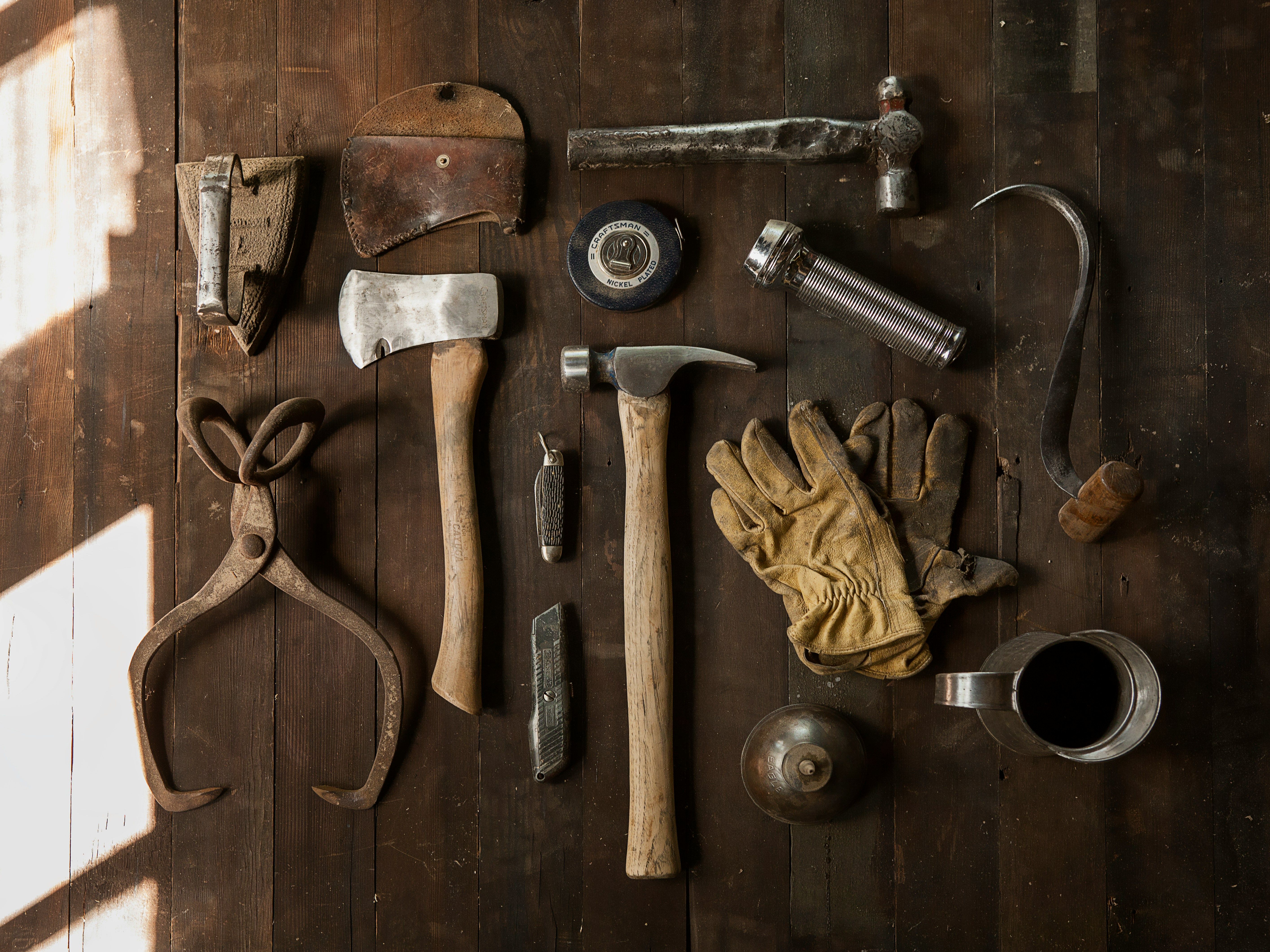 clothes iron, hammer, axe, flashlight and pitcher on brown wooden table