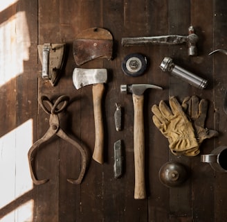clothes iron, hammer, axe, flashlight and pitcher on brown wooden table