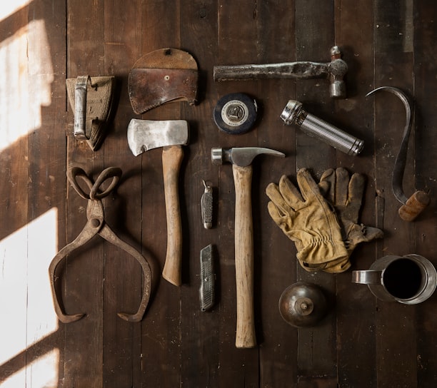 clothes iron, hammer, axe, flashlight and pitcher on brown wooden table
