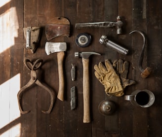 clothes iron, hammer, axe, flashlight and pitcher on brown wooden table