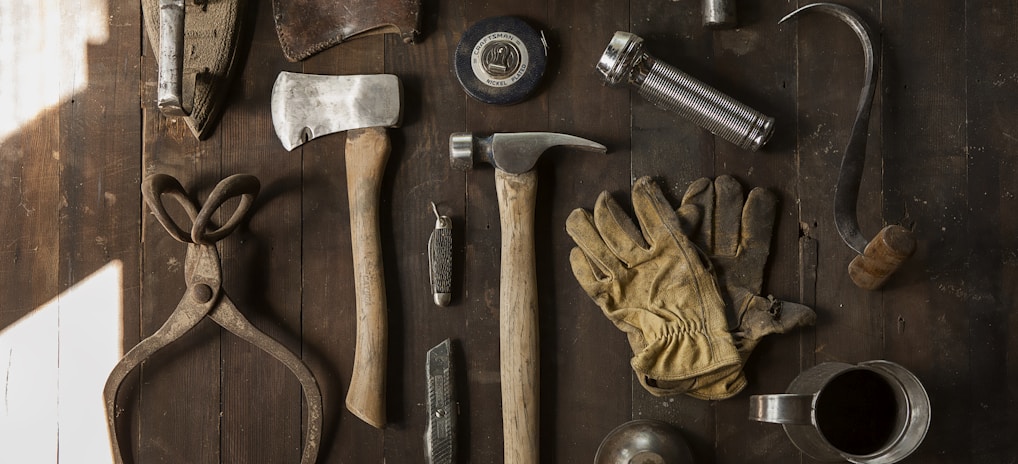 clothes iron, hammer, axe, flashlight and pitcher on brown wooden table