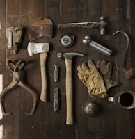 clothes iron, hammer, axe, flashlight and pitcher on brown wooden table