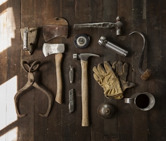 clothes iron, hammer, axe, flashlight and pitcher on brown wooden table