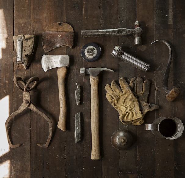 clothes iron, hammer, axe, flashlight and pitcher on brown wooden table