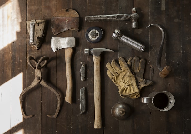 clothes iron, hammer, axe, flashlight and pitcher on brown wooden table