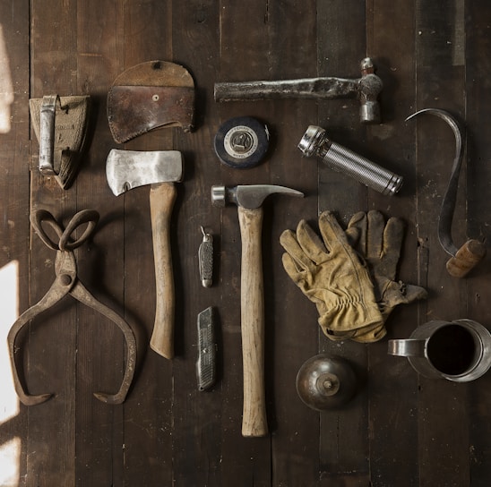 clothes iron, hammer, axe, flashlight and pitcher on brown wooden table