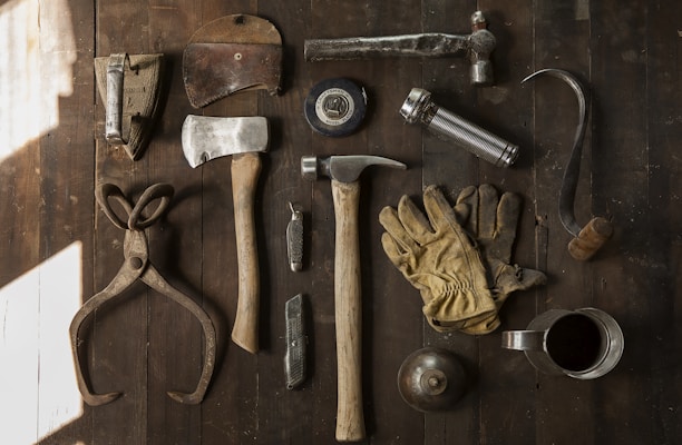 clothes iron, hammer, axe, flashlight and pitcher on brown wooden table
