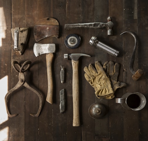 clothes iron, hammer, axe, flashlight and pitcher on brown wooden table