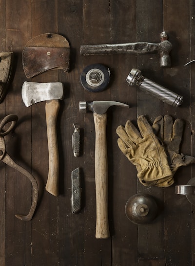 clothes iron, hammer, axe, flashlight and pitcher on brown wooden table