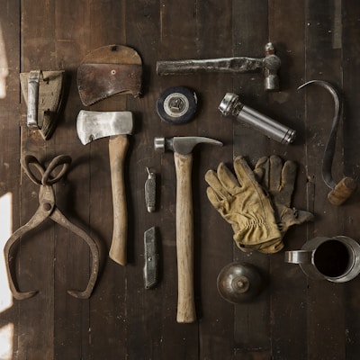 clothes iron, hammer, axe, flashlight and pitcher on brown wooden table