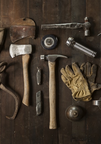 clothes iron, hammer, axe, flashlight and pitcher on brown wooden table