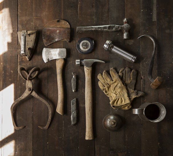 clothes iron, hammer, axe, flashlight and pitcher on brown wooden table