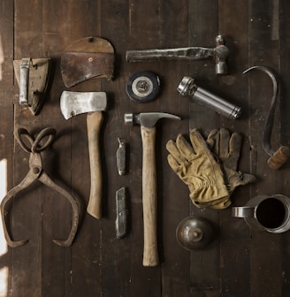 clothes iron, hammer, axe, flashlight and pitcher on brown wooden table