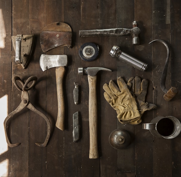 clothes iron, hammer, axe, flashlight and pitcher on brown wooden table