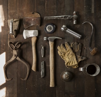 clothes iron, hammer, axe, flashlight and pitcher on brown wooden table