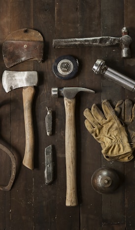 clothes iron, hammer, axe, flashlight and pitcher on brown wooden table
