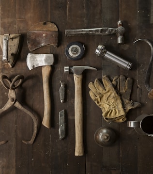 clothes iron, hammer, axe, flashlight and pitcher on brown wooden table