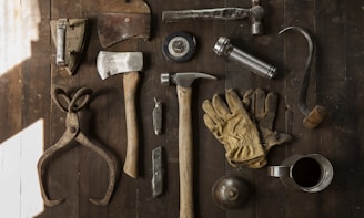 clothes iron, hammer, axe, flashlight and pitcher on brown wooden table
