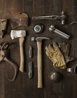 clothes iron, hammer, axe, flashlight and pitcher on brown wooden table