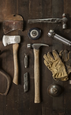 clothes iron, hammer, axe, flashlight and pitcher on brown wooden table