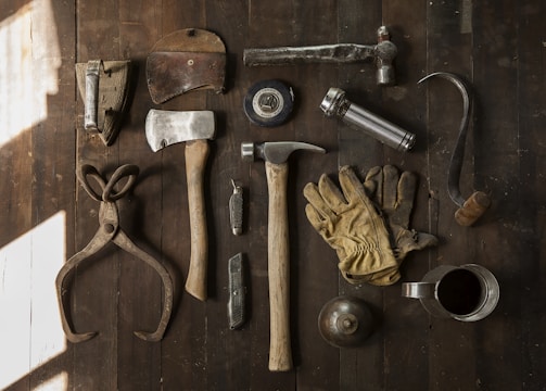 clothes iron, hammer, axe, flashlight and pitcher on brown wooden table