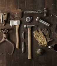clothes iron, hammer, axe, flashlight and pitcher on brown wooden table