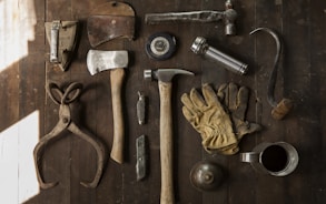 clothes iron, hammer, axe, flashlight and pitcher on brown wooden table