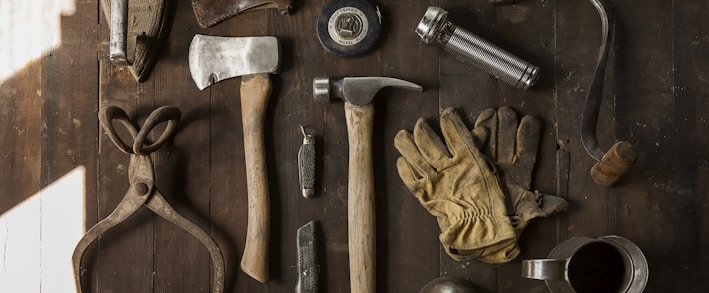 clothes iron, hammer, axe, flashlight and pitcher on brown wooden table