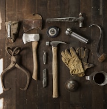 clothes iron, hammer, axe, flashlight and pitcher on brown wooden table