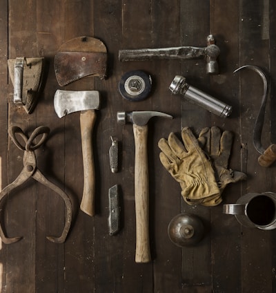 clothes iron, hammer, axe, flashlight and pitcher on brown wooden table