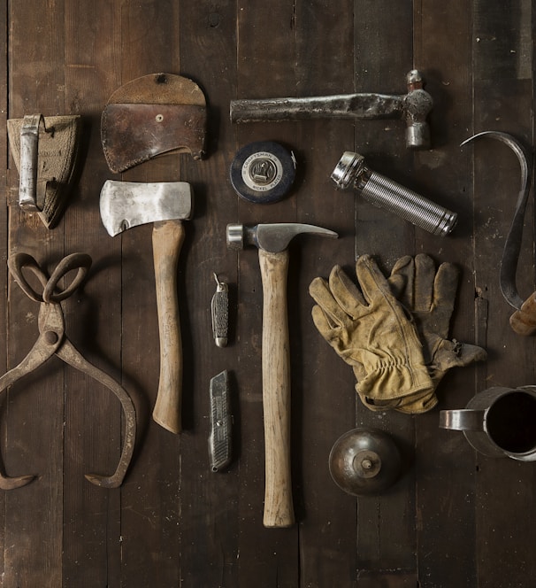 clothes iron, hammer, axe, flashlight and pitcher on brown wooden table