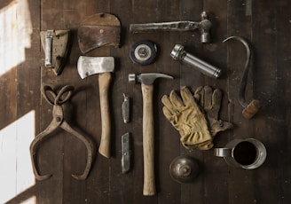 clothes iron, hammer, axe, flashlight and pitcher on brown wooden table