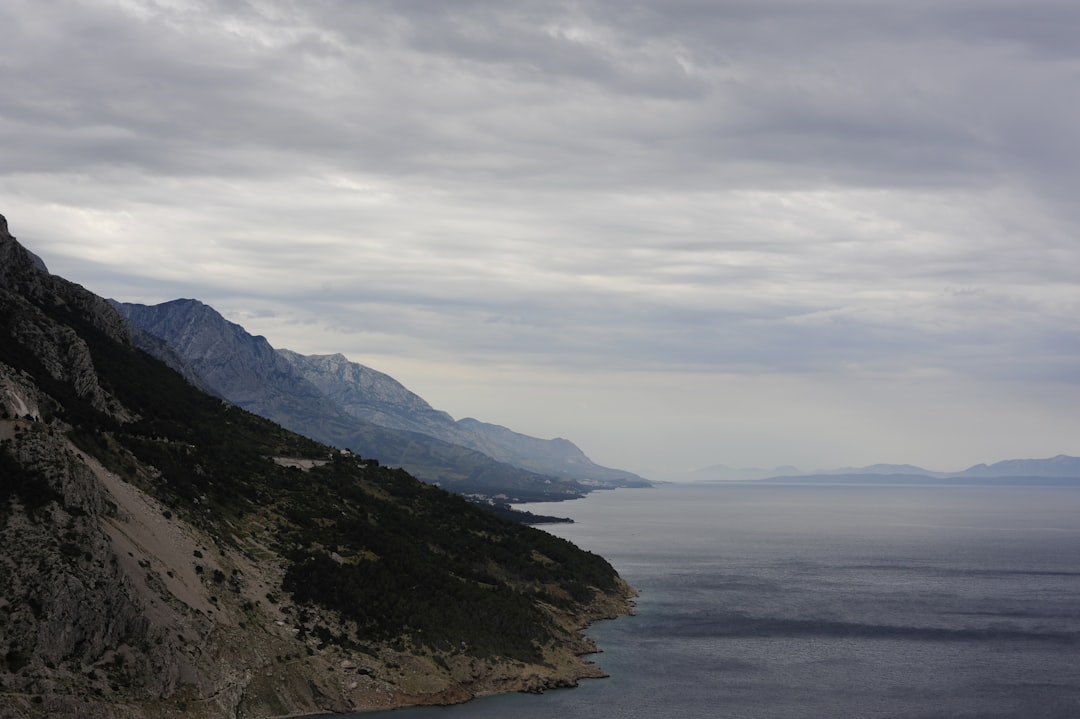 body of water near mountain, Highland coast on a cloudy day