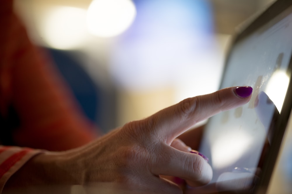 selective focus photography of person pointing at tablet computer