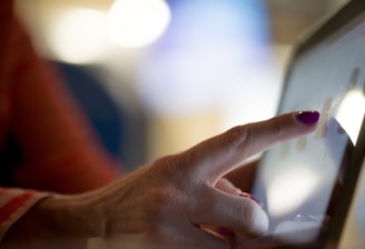 selective focus photography of person pointing at tablet computer