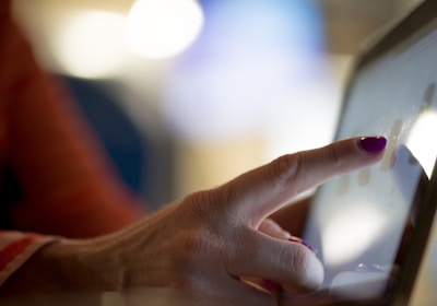 selective focus photography of person pointing at tablet computer
