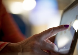 selective focus photography of person pointing at tablet computer