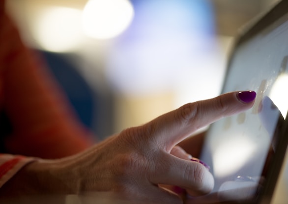 selective focus photography of person pointing at tablet computer