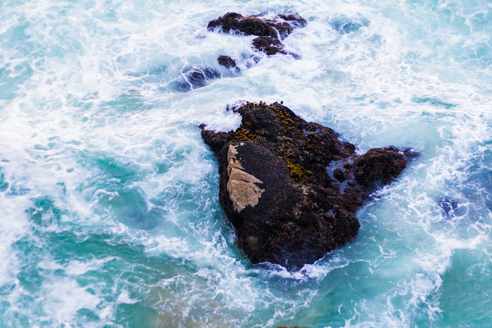 scenery of a rock on a body of water