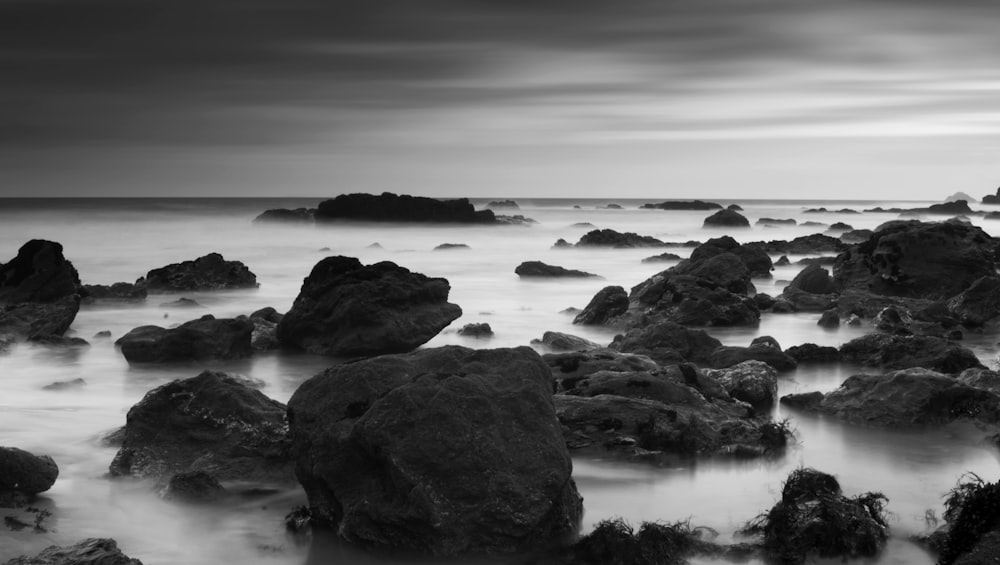 grayscale photography of rocks on body of water