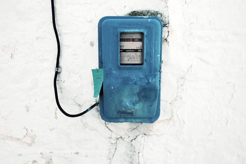 Aparelho eletrônico com fio azul montado na parede pintada de branco