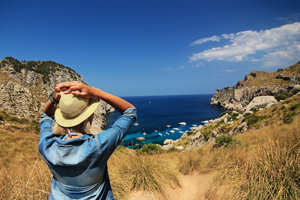 Frau steht auf einer Wiese mit Blick auf ein Gewässer