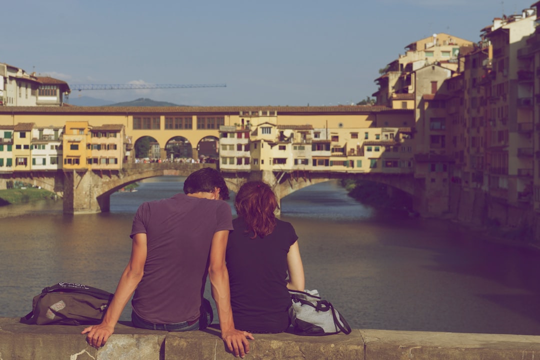 man and woman sitting together in front of body of water during daytime