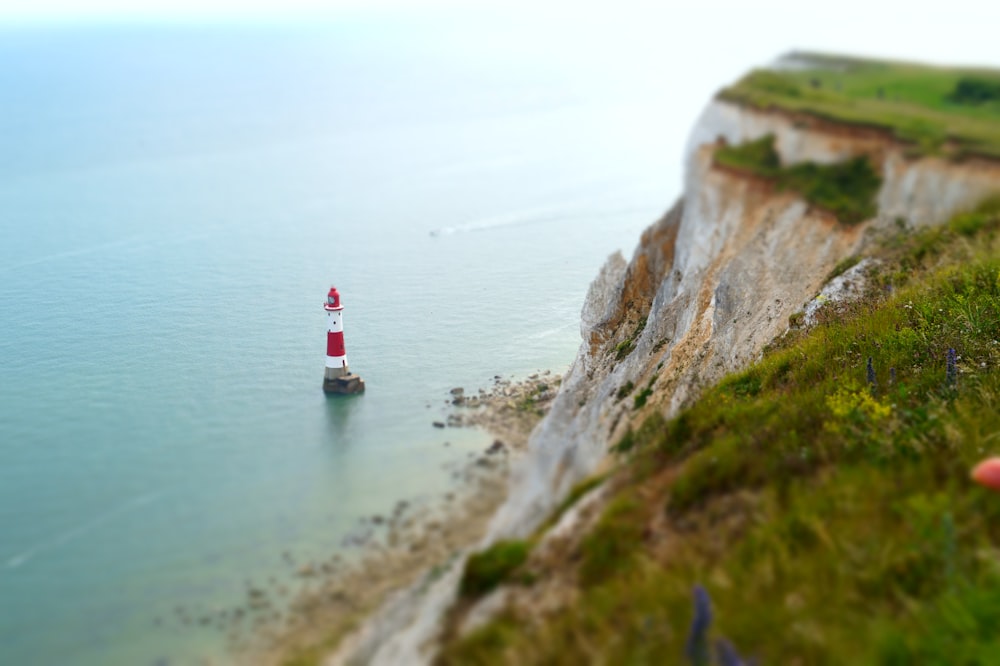 aerial photograph of red and white lighthouse on rock