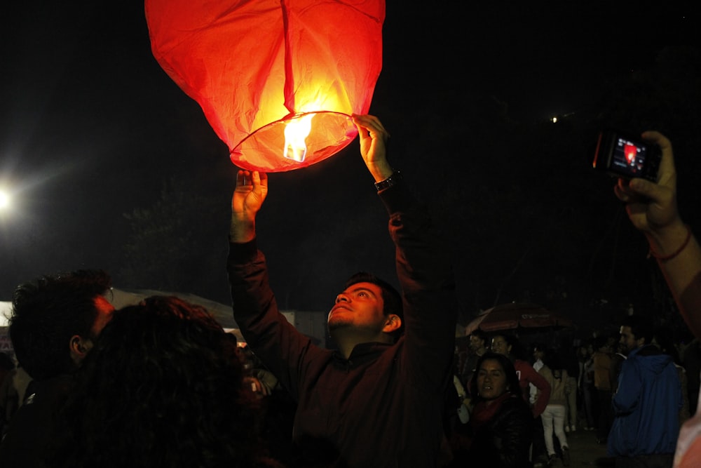 man holding lighted sky lantern