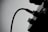 A black and white silhouette of a cable plugged into a device with visible knobs and a socket. The image focuses on the curved cable, creating a contrast against the light background.